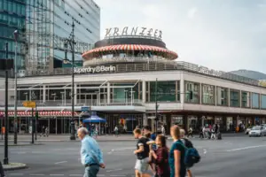 Berlin Sightseeing Café Kranzler Kurfürstendamm Die markante Rotunde des Café Kranzler am Berliner Kurfürstendamm mit Passanten im Vordergrund und moderner City-West-Architektur.