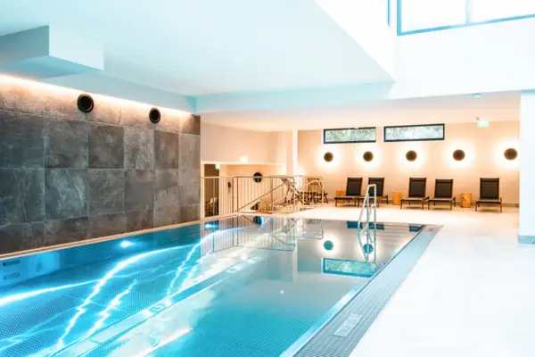 Innenpool mit Treppe und Stühlen.