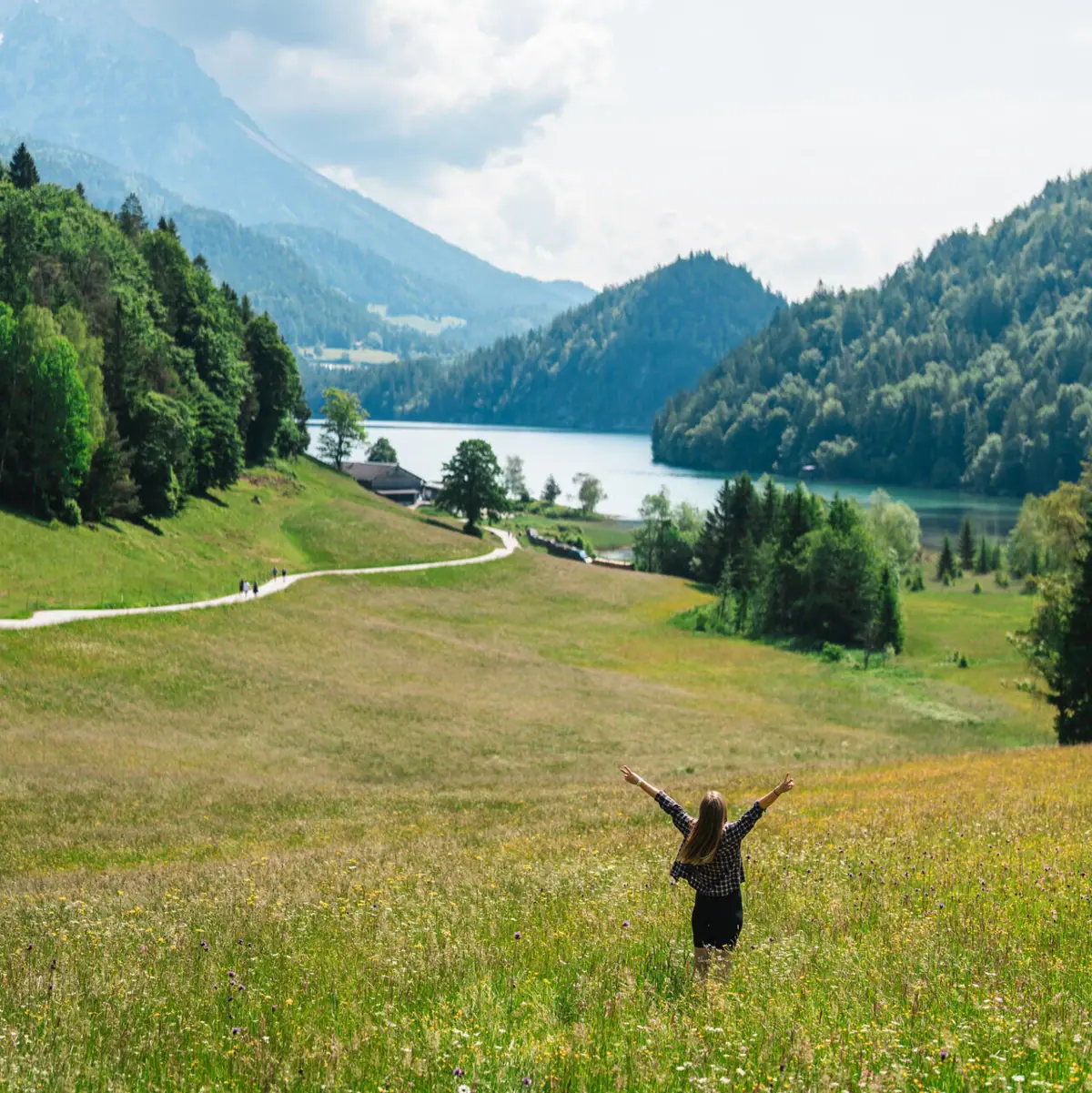 Kitzbüheler Alpen Eine Frau steht mit erhobenen Armen in einem Feld.