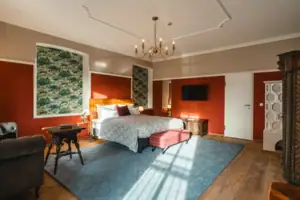 Das Hotelzimmer Salon im HENRI Hotel Kitzbühel mit roten Wänden und einem großen Bett.