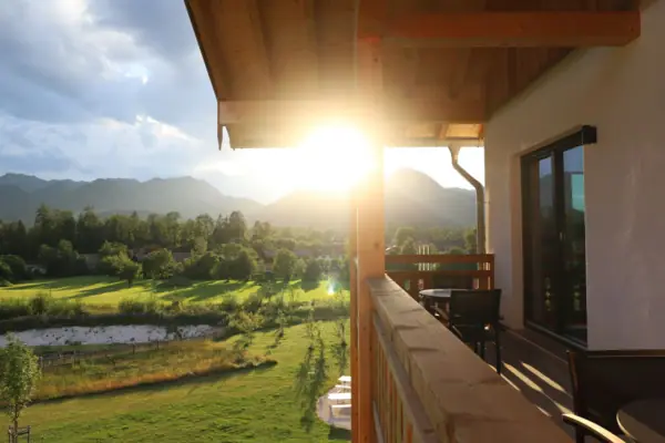 Sonne scheint durch die Bäume auf eine Veranda Balkones im aja Riuhpolding.