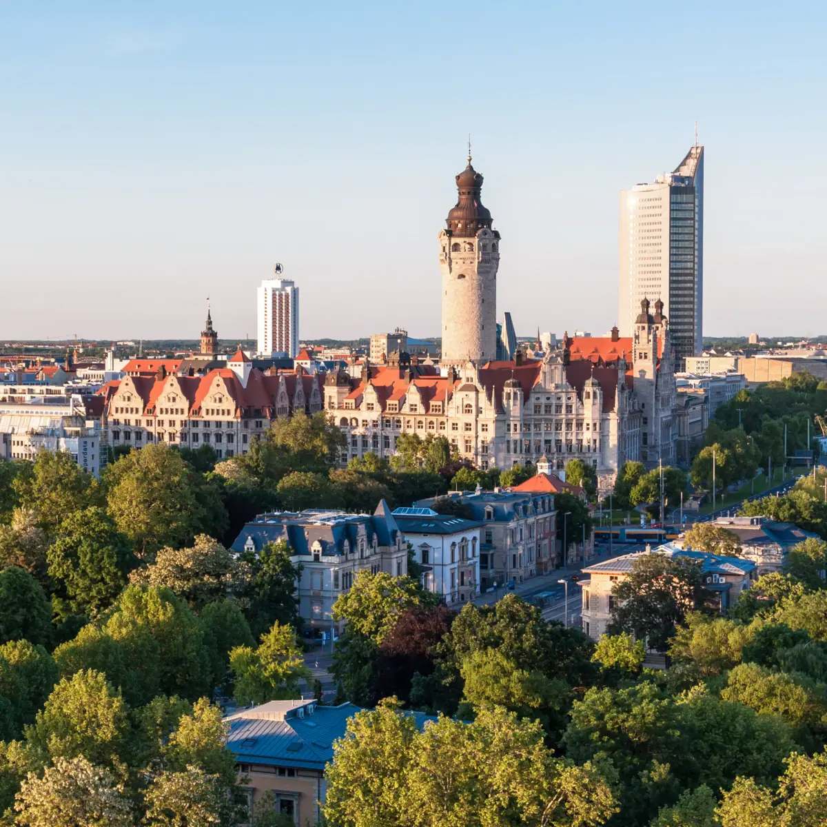 Die Skyline von Leipzig mit Bäumen und Gebäuden im Morgenlicht.