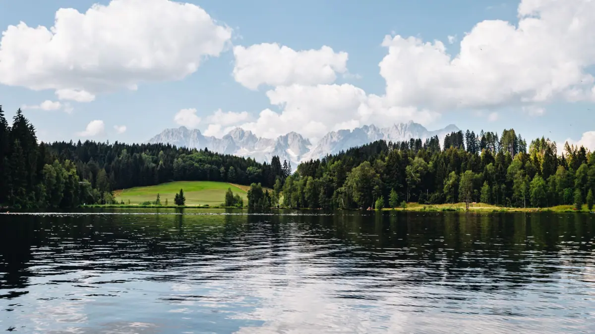 Kitzbühel Schwarzsee Der Schwarzsee mit Bäumen und Bergen im Hintergrund.