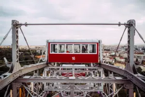 Rotes und weißes Riesenrad vor bewölktem Himmel.