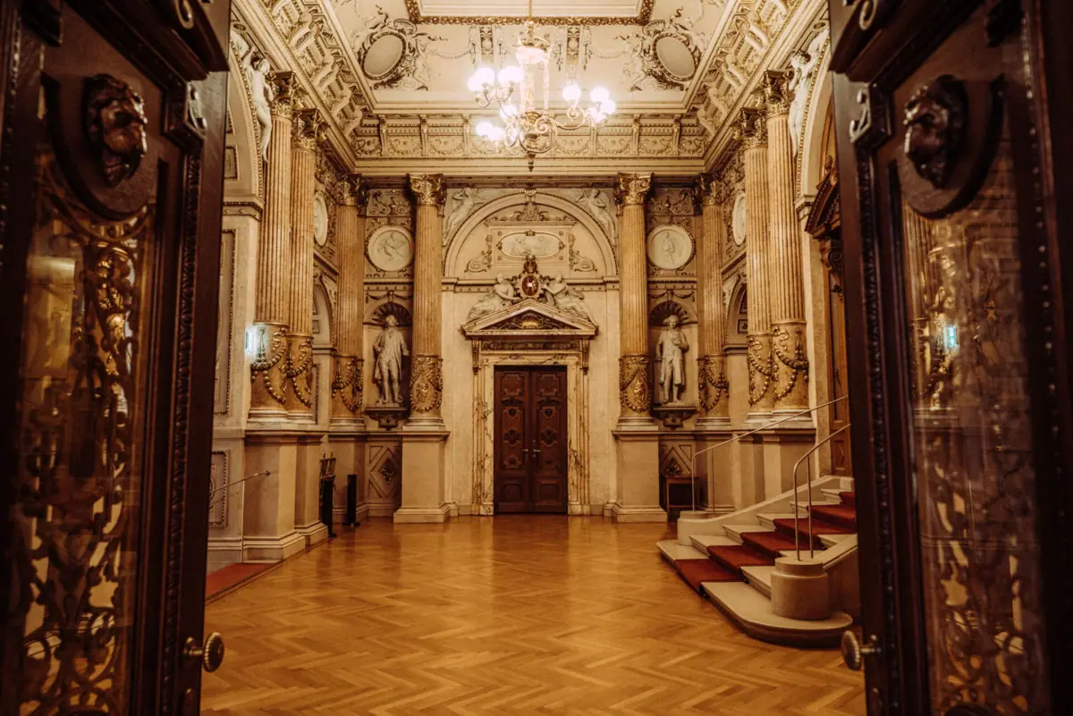 Großer, reich verzierter Raum mit Treppe und Kronleuchter im Napoleon-III-Stil.