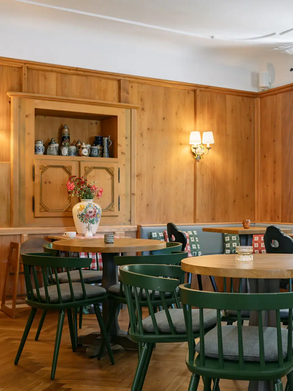 In einem urigen Raum mit Holzwänden steht ein Tisch mit einer Vase voller Blumen.