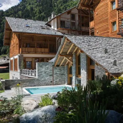 Ein Hotel mit Pool im Vordergrund und Bergen im Hintergrund.