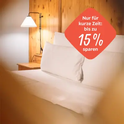 Bett mit weißen Laken und einer Lampe