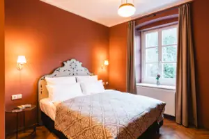 Ein Zimmer mit Bett und einem Fenster mit Blick ins Grüne