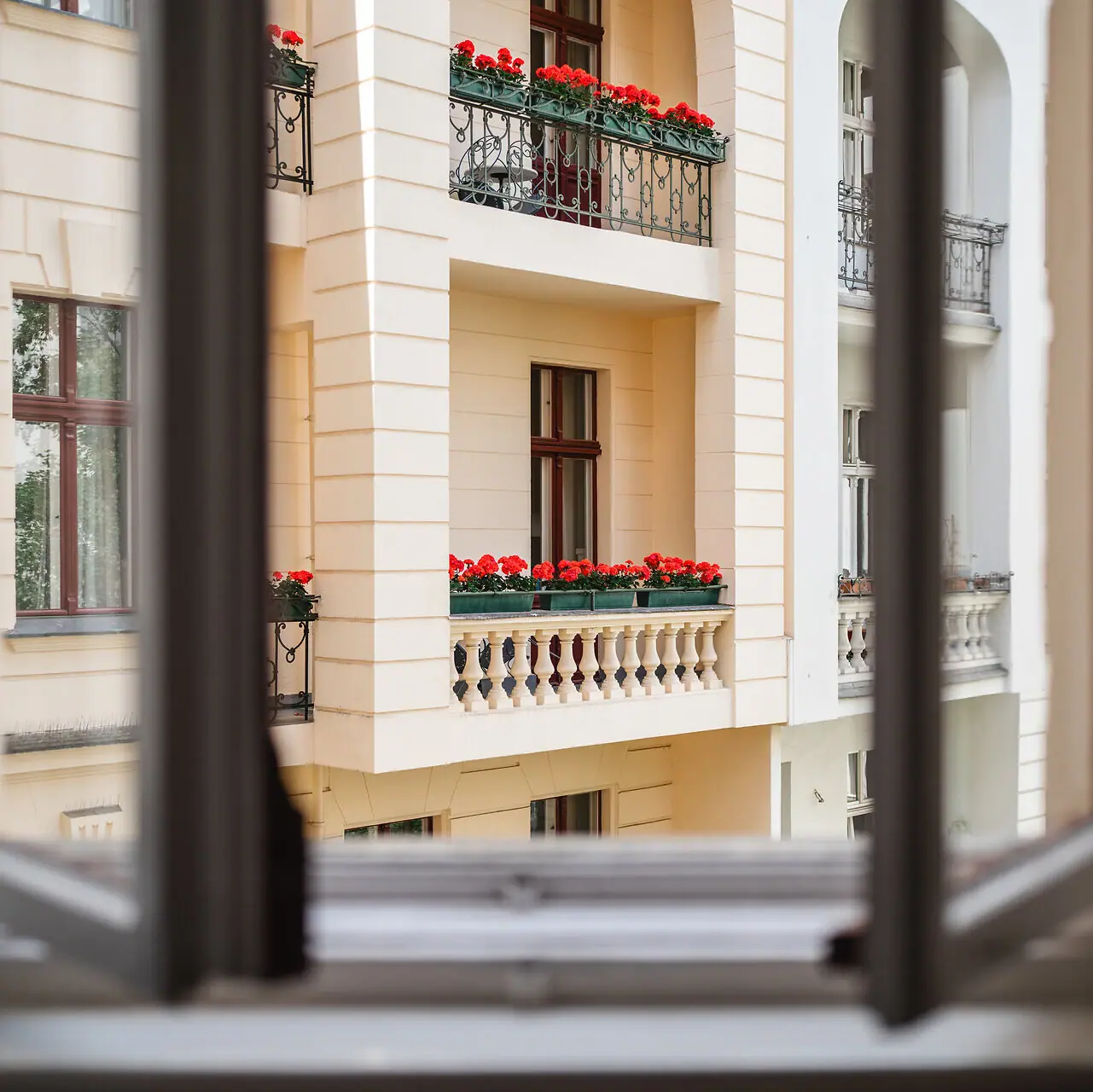 Ein Fenster mit Blick auf ein Gebäude mit Blumen auf dem Balkon.