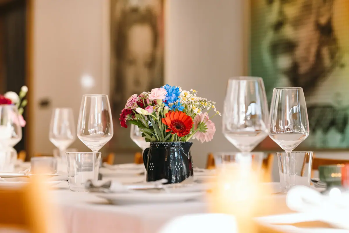 Ein Tisch mit Gläsern und einer Vase mit Blumen.