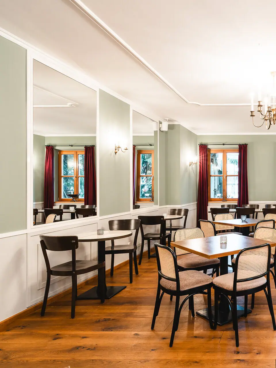 Ein heller Raum mit Tischen und Stühlen und Spiegeln an den Wänden.