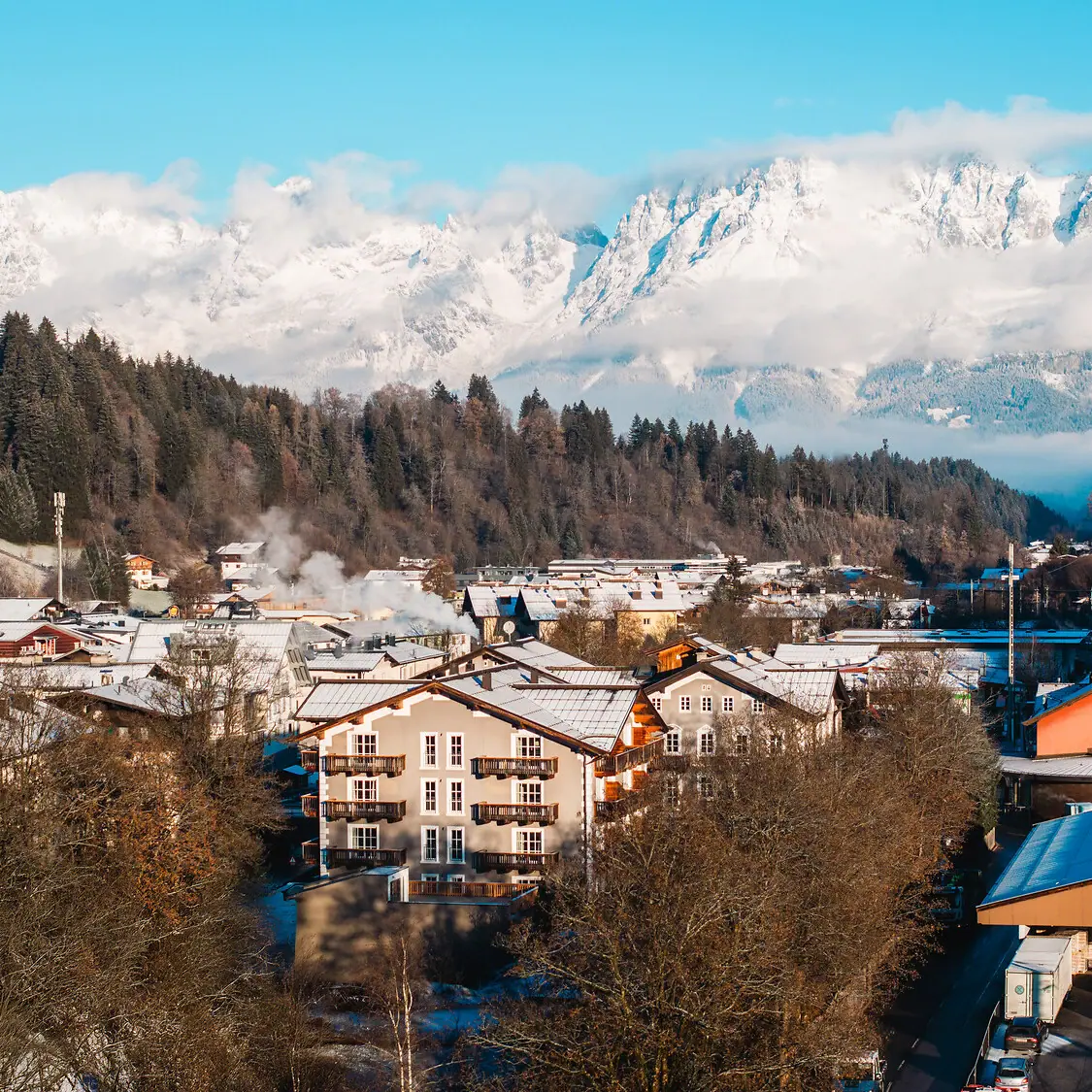 Bergdorf mit schneebedeckten Bergen im Hintergrund.