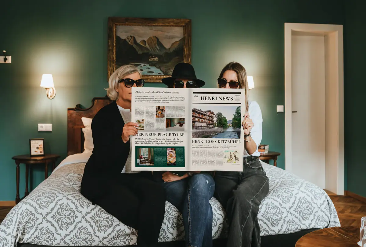 Eine Gruppe von Menschen sitzt auf einem Bett und liest eine Zeitung.