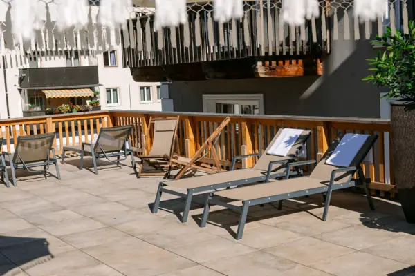 Eine Terrasse mit Stühlen und einem weißen Sonnenschirm.