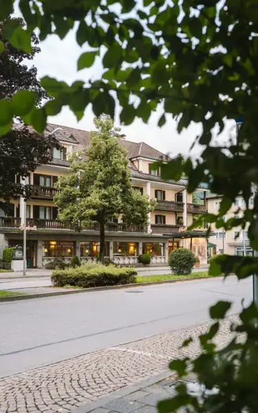 Fluss fließt an einem Gebäude und Bäumen vorbei.