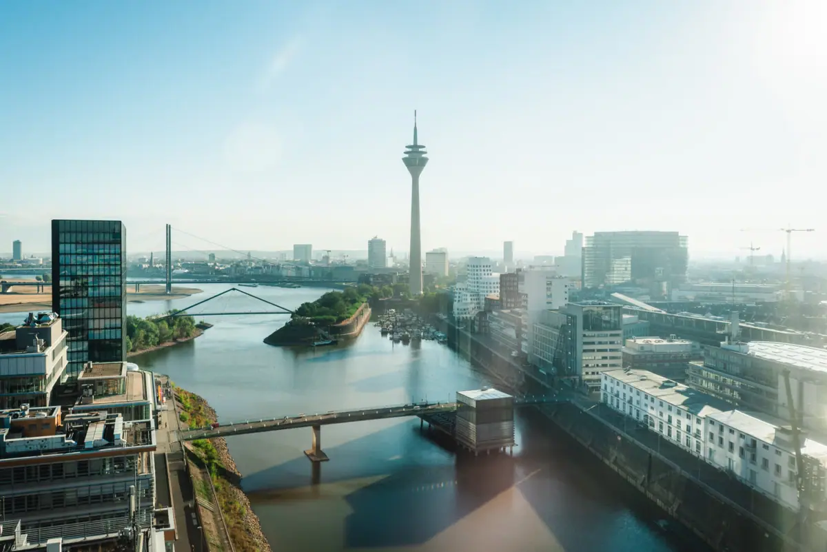 Fluss mit Brücke und Stadt im Hintergrund, dominiert von einem Turm.