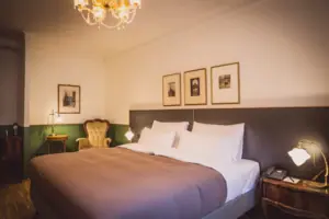 Ein Bett mit einem Kronleuchter und Bildern an der Wand.