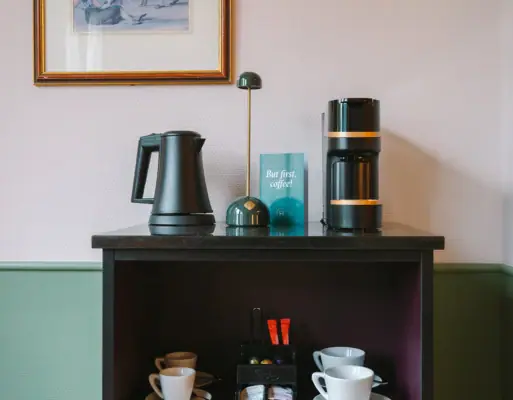 Eine Zimmerbar in einem Hotelzimmer des HENRI Hotels in Garmisch-Partenkirchen mit einer Kaffee- und Teestation.