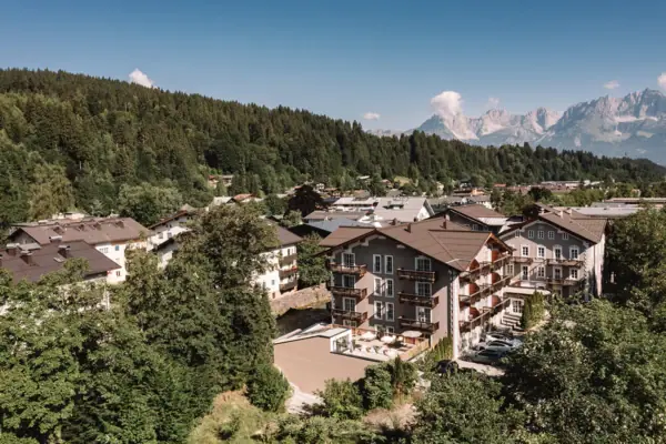 Eine Gruppe von Gebäuden mit Bäumen und Bergen im Hintergrund.