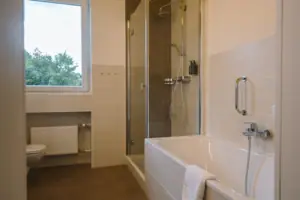 HENRI GAP Salon mit Balkon Badezimmer mit Dusche und Badewanne, ausgestattet mit modernen Armaturen und Spiegel.