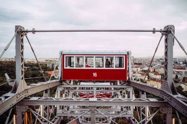 Rotes und weißes Riesenrad vor bewölktem Himmel.