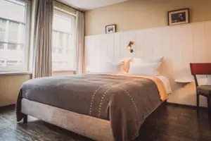 Bett mit Lampe und Fenster im stilvollen Hotelzimmer.