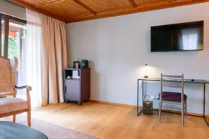 Schreibtisch im HENRI Garmisch-Partenkirchen Ein Zimmer mit einem Fernseher und einem Tisch.