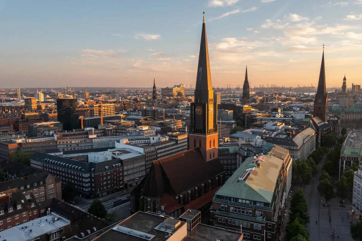 Stadtansicht mit hohem Kirchturm und leicht bewölktem Himmel.