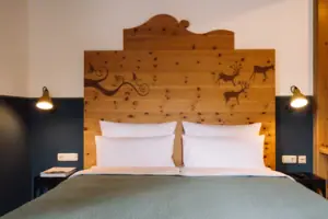HENRI GAP Salon mit Balkon Bett mit Holz-Kopfteil und weißer Bettwäsche in einem Hotelzimmer