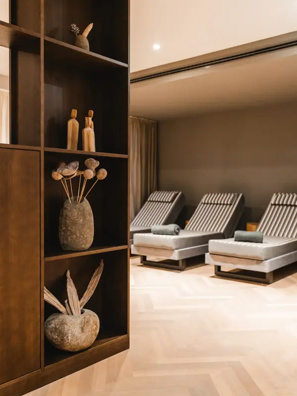 Ein Raum mit Stühlen und einem Regal mit Vasen und Blumen.