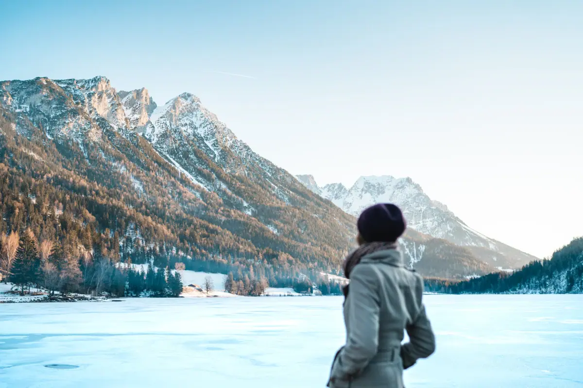 Eine Frau steht vor einer Schneelandschaft mit Bergen im Hintergrund.