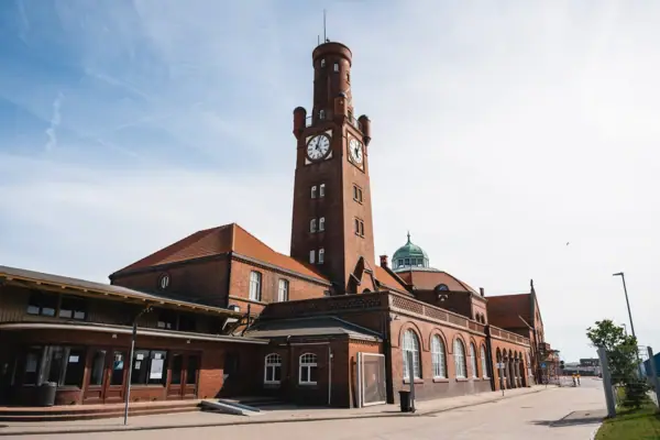 Hapag-Hallen in Cuxhaven als Backsteingebäude mit Uhrturm unter bewölktem Himmel.
