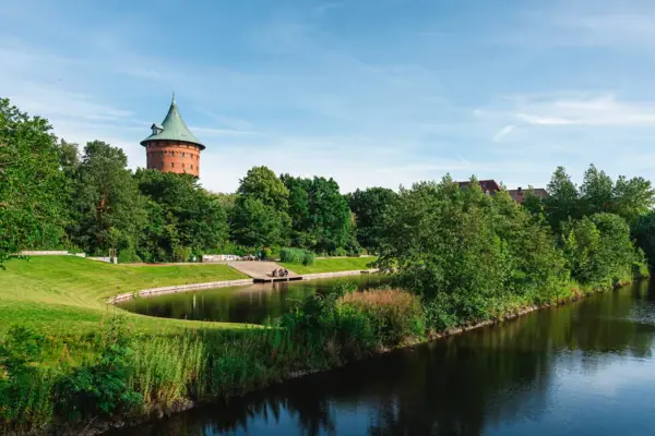Wasserweg mit Bäumen und dem Wasserturm in Cuxhaven im Hintergrund.
